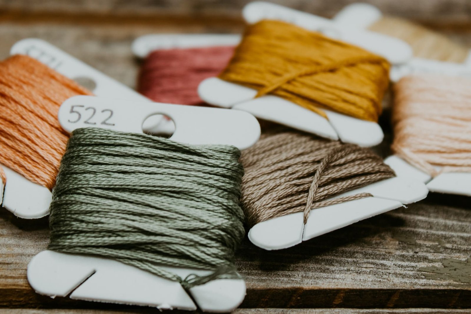 Green and yellow yarn in spools on brown wooden table